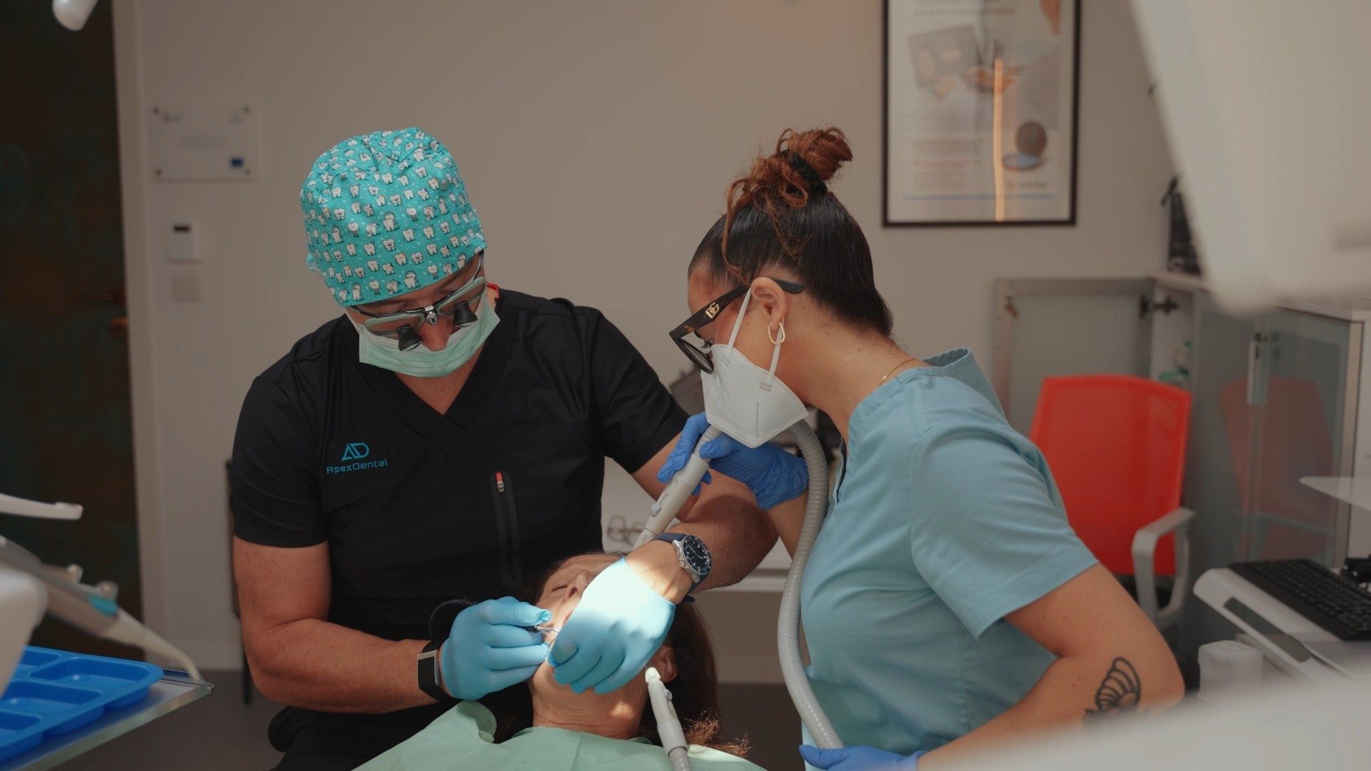 A dentist and dental assistant treating a patient at Apex Dental